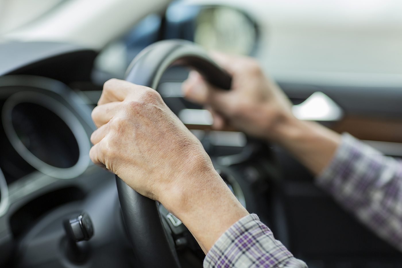 Close-up of a driver's hands on the steering wheel of a car